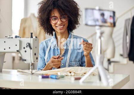 Happy African-American Kleidung Designer schießt Tutorial für Anhänger in geräumigen Werkstatt Stockfoto