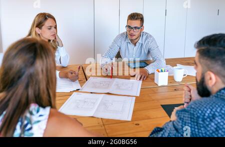 Geschäftsleute bei einem Arbeitstreffen mit Blick auf Konstruktionszeichnungen Stockfoto