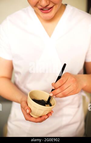 Inhalt weibliche Kosmetikerin Vorbereitung Ton Gesichtsmaske für die Hautpflege Behandlung im Schönheitssalon und Blick auf die Kamera Stockfoto