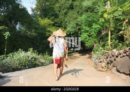 LANJIA SAORA STAMM. Lanjia Saora Bauer trägt traditionelle Lendenschurz und Sanur Regenkappe oder coolie Hut für die Arbeit. Blick von hinten. Gunpur Village Stockfoto