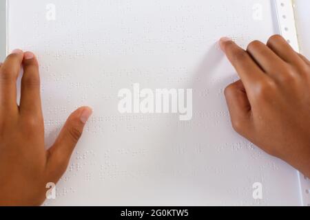 Hände eines blinden afroamerikanischen Schuljungen, der mit den Fingern ein Braillebuch liest Stockfoto