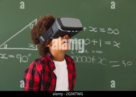 afroamerikanischer Schuljunge mit vr-Headset vor der Tafel im Klassenzimmer Stockfoto