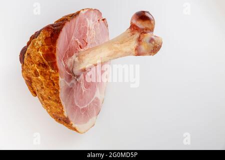 Glasierter Schweineschinken mit großem Knochen auf weißem, isoliertem Hintergrund. Stockfoto