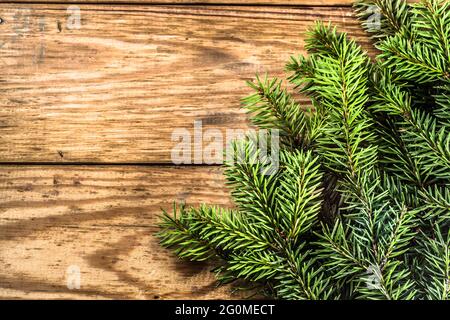 Weihnachtsbaum Zweige der Fichte auf alten Holzplanken Hintergrund als Feiertag Hintergrund im Vintage-Stil angeordnet. Stockfoto