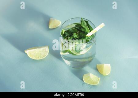 Mojito trinkt mit Stroh auf dem blauen Tisch. Kaltes erfrischendes Getränk mit Minze- und Zitronenscheiben, Draufsicht. Stockfoto