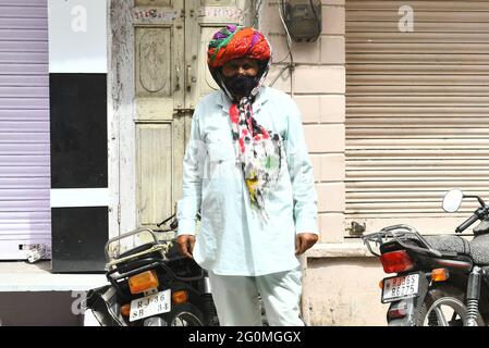 Beawar, Rajasthan, Indien, 1. Juni 2021: Rajasthani Mann in Turban, trägt Gesichtsmaske, stehen vor dem geschlossenen Geschäft auf einem Markt, als Entsperrungsprozess von COVID-19 Lockdown beginnt, in Beawar. Kredit: Sumit-Samarwat/Alamy Live Nachrichten Stockfoto