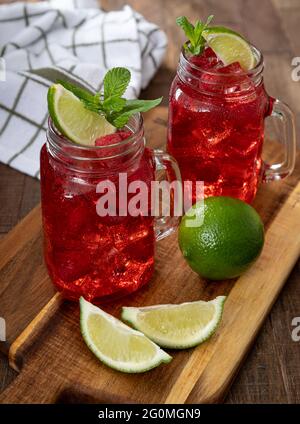 Zwei Gläser Cranberry-Saft mit Himbeeren und Limette Ein rustikaler Holztisch Stockfoto