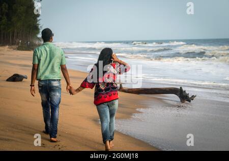 Paar, das am Sandstrand mit der Hand des anderen läuft und das natürliche Meeresbild einsaugend, wird im kochi kerala india aufgenommen und zeigt die Liebe Stockfoto