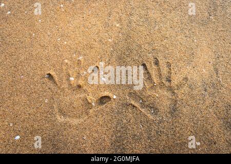 Couple Hand Prints auf gelbem Sandstrand zeigen Liebe für einander und die Natur Stockfoto