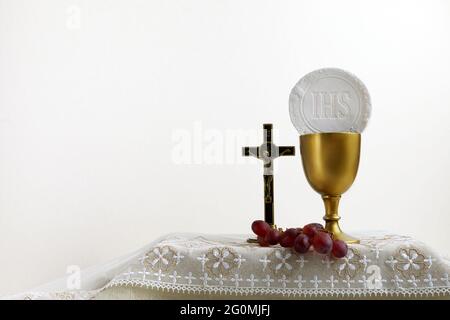 Das Konzept des Fronleichnamsfestes. Heilige Kommunion und Tasse Glas mit Rotwein auf dem Tisch. Stockfoto