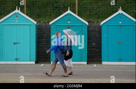 Am Bournemouth Beach in Dorset laufen die Menschen an Strandhütten vorbei. Bilddatum: Mittwoch, 2. Juni 2021. Stockfoto