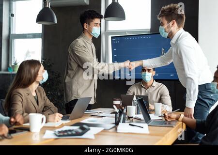 Porträt von verschiedenen Geschäftsleuten in Masken, die Faustschlag geben Stockfoto
