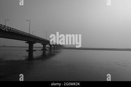 Straßenbrücke über den Fluss mit seiner Wasserspiegelung in der Morgendämmerung aus niedrigen Winkel schwarz-weiß-Bild wird an Koshi Brücke bihar indien genommen. Es ist die längste Stockfoto