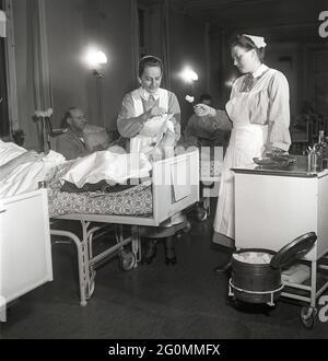 Krankenhaus in den 1950er Jahren. Zwei Krankenschwestern mit einem Patienten, der eine Verletzung am Fuß hat und der Verband geändert werden muss. Schweden 1951 Ref. BB38-2 Stockfoto
