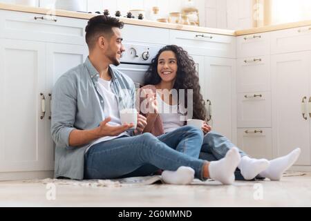 Häusliche Entspannung. Arabische Ehegatten Trinken Kaffee, Während Sie Auf Dem Boden In Der Küche Sitzen Stockfoto