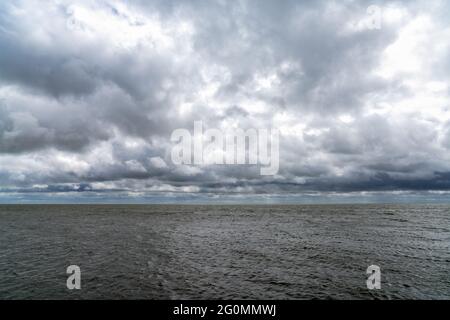 Landschaft mit ausdrucksstarkem bewölktem und bewölktem Himmel über einem windgeschlagenen Wattenmeer in den Niederlanden Stockfoto