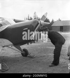 Flugzeug in den 1950er Jahren. Ein Mann steht neben einem kleinen Flugzeug und ist neugierig, was sich darin befindet. Er schaut gut in die Vorderseite des Flugzeugs. Laut der Originalunterschrift ist er skeptisch, ein Passagier in dem kleinen Flugzeug zu sein, das er für nicht sicher hält. Schweden 1952 Ref. AY40-4 Stockfoto