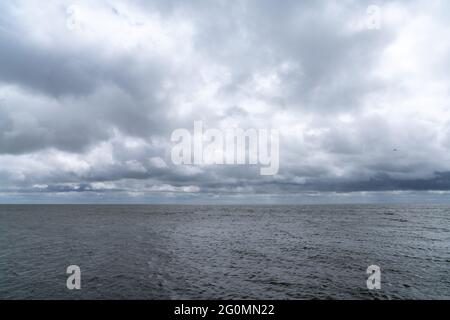 Landschaft mit ausdrucksstarkem bewölktem und bewölktem Himmel über einem windgeschlagenen Wattenmeer in den Niederlanden Stockfoto