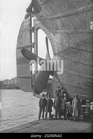 Dockyard in den 1920er Jahren. Ein Schiff wird gewartet und das Schiff wird in einem Trockendock angestiegen. Einer der Hecks des Propellers ist sichtbar und seine Größe kann gemessen werden, indem man ihn mit den Menschen vergleicht, die darunter stehen. Foto aufgenommen in der Götaverken Werft in Göteborg Schweden in den 1920er Jahren. Stockfoto