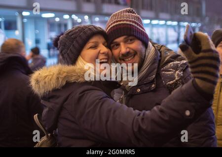 Junges Paar lächelt und nimmt ein Selfie während des Winterfestes Stockfoto