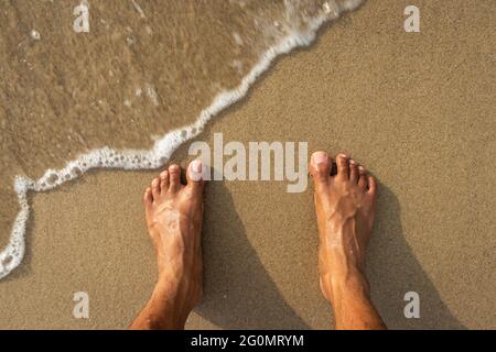 Menschliche Füße fühlen die Natur isoliert am Sandstrand und zeigen die menschliche Liebe zur Natur. Der wahre Ausdruck des menschlichen Lebens. Stockfoto