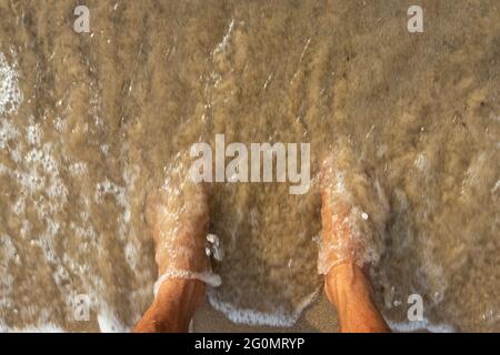 Menschliche Füße fühlen die Natur isoliert am Sandstrand und zeigen die menschliche Liebe zur Natur. Der wahre Ausdruck des menschlichen Lebens. Stockfoto