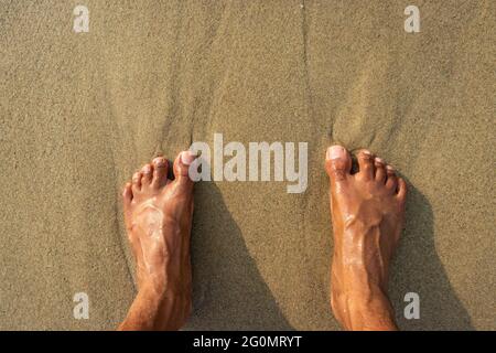 Menschliche Füße fühlen die Natur isoliert am Sandstrand und zeigen die menschliche Liebe zur Natur. Der wahre Ausdruck des menschlichen Lebens. Stockfoto