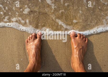 Menschliche Füße fühlen die Natur isoliert am Sandstrand und zeigen die menschliche Liebe zur Natur. Der wahre Ausdruck des menschlichen Lebens. Stockfoto