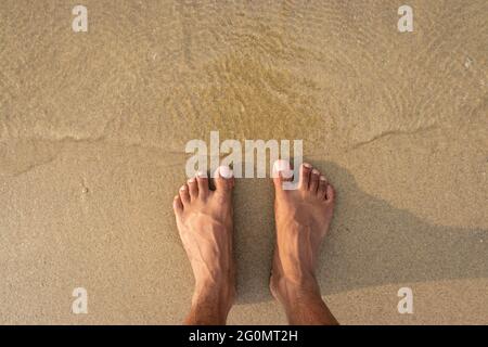 Menschliche Füße fühlen die Natur isoliert am Sandstrand und zeigen die menschliche Liebe zur Natur. Der wahre Ausdruck des menschlichen Lebens. Stockfoto