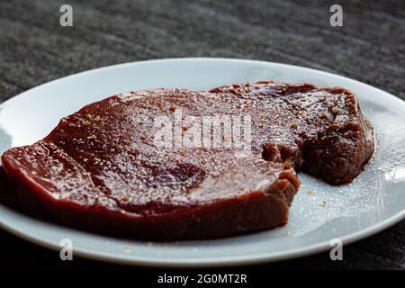 Rohes, gewürztes und gesalzenes Steak, das vor dem Kochen ruht Stockfoto