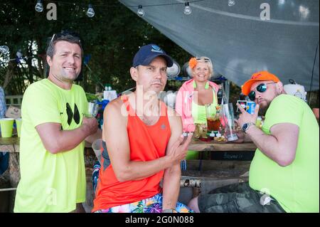 Eine Gruppe von Freunden und Menschen in Neon gekleidet bei einem Sommerfest auf einem Feld. Stockfoto