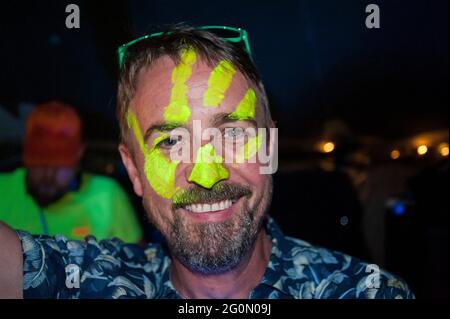 Eine Gruppe von Freunden und Menschen in Neon gekleidet bei einem Sommerfest auf einem Feld. Stockfoto