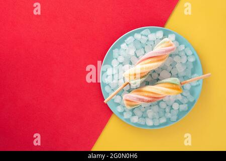 Spirale bunte Eiszapfen auf rotem und gelbem Hintergrund Stockfoto
