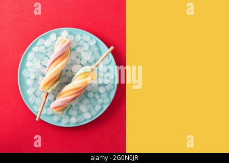 Spirale bunte Eiszapfen auf rotem und gelbem Hintergrund Stockfoto