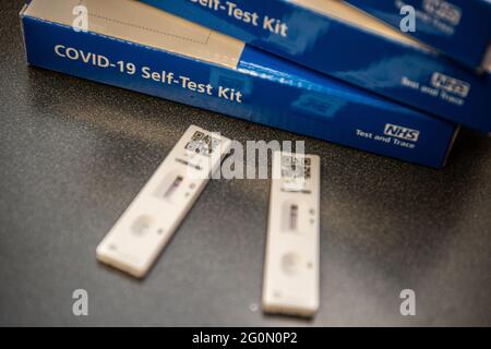 COVID-19 Selbsttestkits, gestapelt auf einem Tisch. Die Seite des blauen COVID-Testkits ist deutlich sichtbar Stockfoto