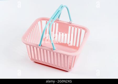 Farbenfroher Einkaufskorb aus Kunststoff. Leerer rosafarbener und blauer Supermarkt-Korb auf hellem Hintergrund. Kreatives minimalistisches Design, Online-Shopping. Schwarz Stockfoto