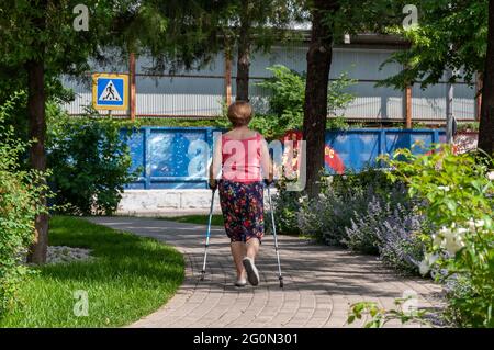 Krasnodar, Russland - 1. Juni 2021: Aktive ältere Frau, die im Park Nordic Walking mit Stöcken praktiziert Stockfoto