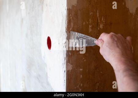 Reparatur der Wand - Mann, der Spachel auf ein Loch in der Wand setzt Stockfoto