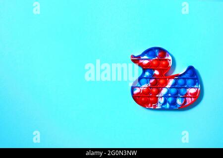 Trendy Pop it Spielzeug in Form von Ente auf blauem Hintergrund. Draufsicht Flat Lay. Speicherplatz Kopieren. Stockfoto