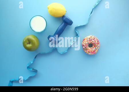Maßband um eine Hantel gewickelt und Donuts auf dem Tisch Stockfoto