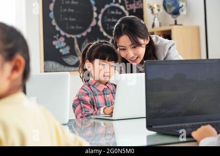 Der Lehrer, der die Kinder berät, benutzt den Computer Stockfoto