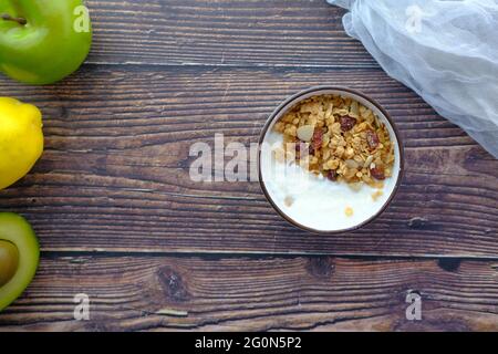 Joghurt, Müsli, Frühstück in einer Schüssel auf Holzhintergrund Stockfoto