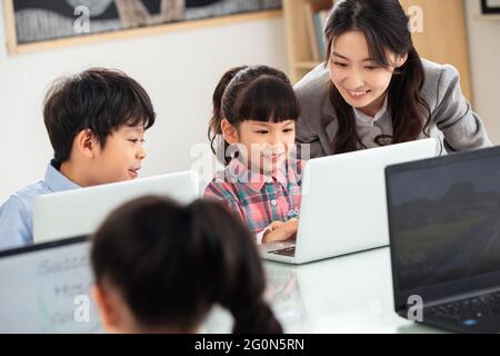 Der Lehrer, der die Kinder berät, benutzt den Computer Stockfoto