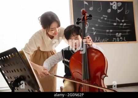 Die junge Frau, die Studenten beim Cello-Lernen anleitet Stockfoto