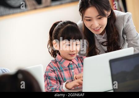 Der Lehrer, der die Kinder berät, benutzt den Computer Stockfoto
