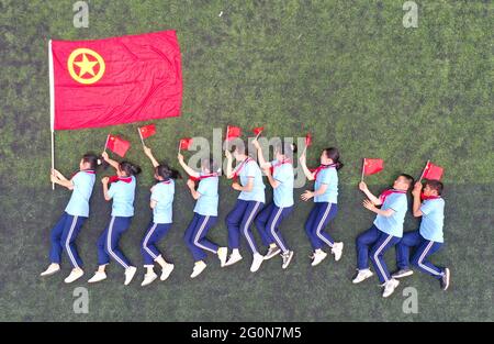 1. Juni 2021, Chuzhou, China: Schüler der Shiji-Schule im Bezirk Nanqiao, Stadt Chuzhou, Provinz Anhui, halten eine kleine rote Flagge und machen ein Gruppenfoto mit der Flagge des chinesischen Jugendpionierenteams. Am selben Tag starteten die Shiji-Schule im Bezirk Nanqiao, Stadt Chuzhou, Provinz Anhui und das Energieversorgungsunternehmen Chuzhou Suburban gemeinsam die thematische Bildungsaktion „Ich liebe das Mutterland und feiere den 1. Juni“. Die Studenten und Mitarbeiter der Stromversorgung winkten gemeinsam auf dem Campus die fünf-Sterne-rote Fahne, sangen gemeinsam ''My Motherland and Me'' und hatten eine andere Art von ''Children's Day' (Credi Stockfoto