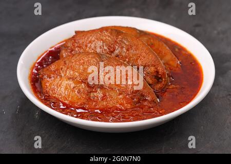 Seer Fish, traditionelles indisches Fisch-Kerrecury, in einer weißen Keramikschale auf einem grauen strukturierten Hintergrund angeordnet, isoliert. Stockfoto