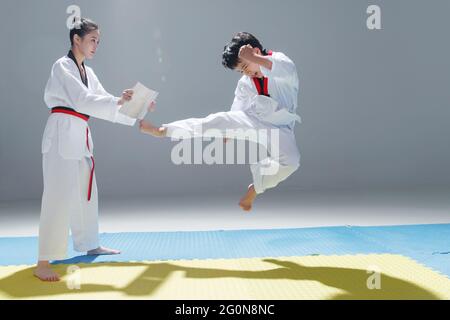 Der junge Trainer lehrte den kleinen Jungen Tae Kwon zu lernen Stockfoto