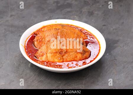 Seer Fish, traditionelles indisches Fisch-Kerrecury, in einer weißen Keramikschale auf einem grauen strukturierten Hintergrund angeordnet, isoliert. Stockfoto