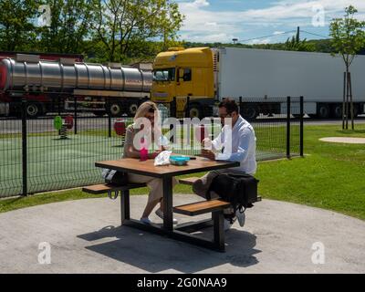 Paris, Frankreich, Mai 2021. Die Reise, eine Pause für ein Essen auf einem Parkplatz, eine Bank mit einem Tisch, ein Paar von Mann und Frau sitzen, ausruhen, essen ein Stockfoto